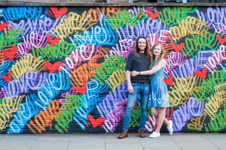 Couple stood in front of love street art