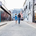 Couple walking down a Shoreditch street with graffiti