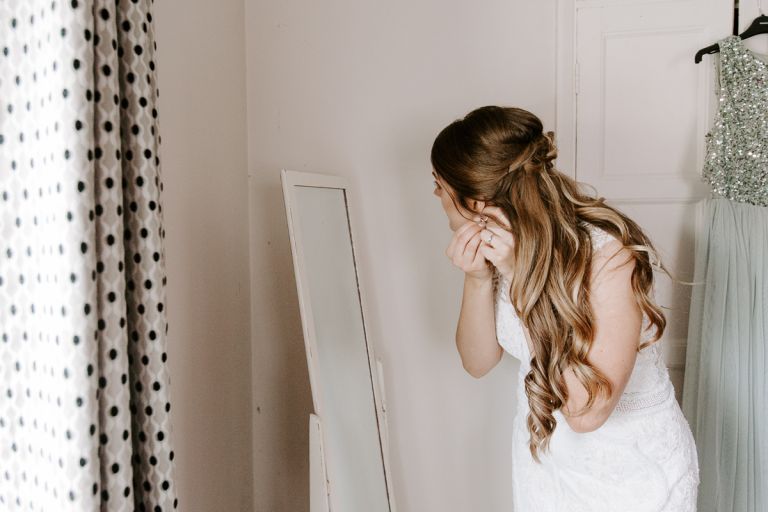 Bride putting her earrings in before wedding