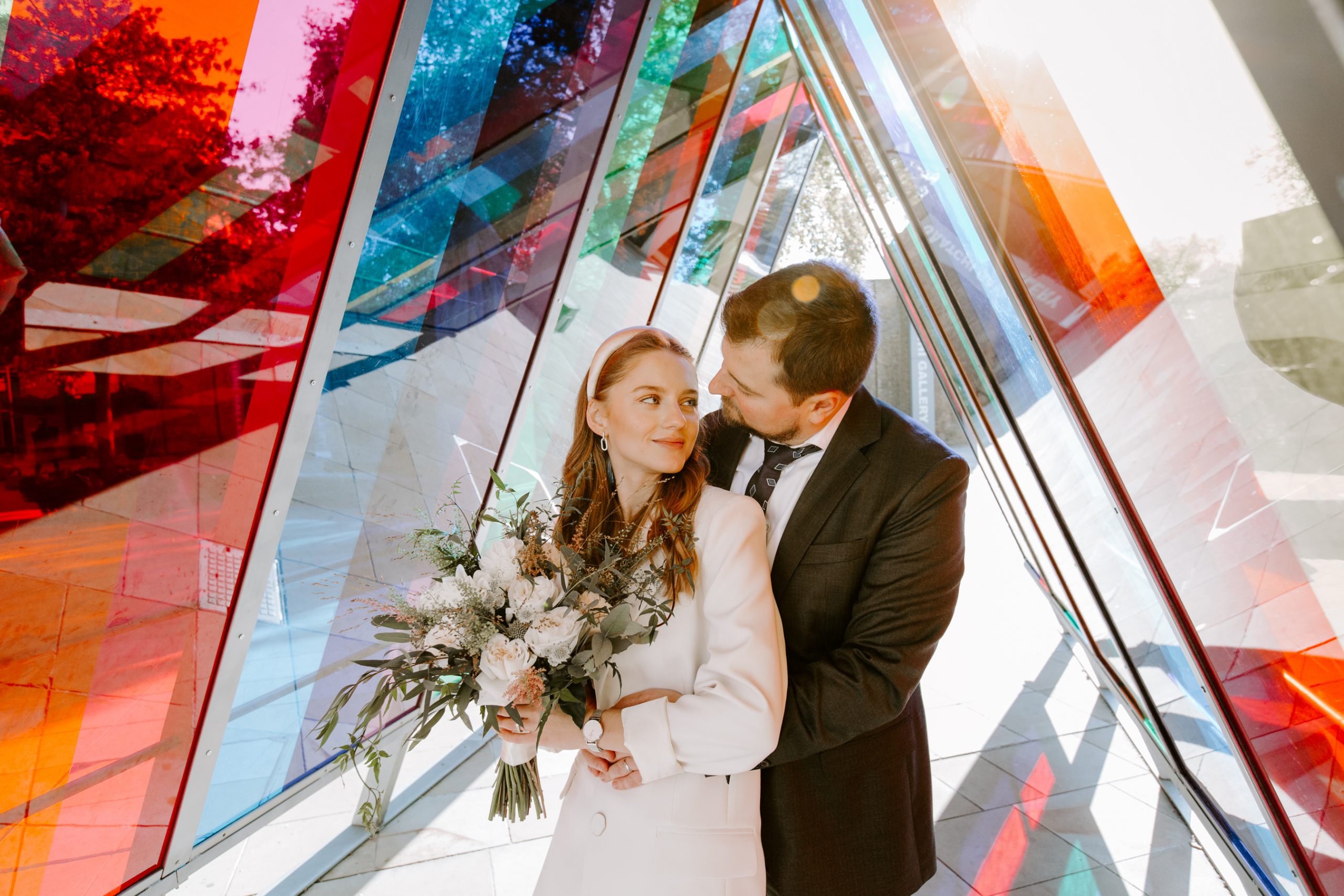Bride and groom smiling in a coloured light tunnel