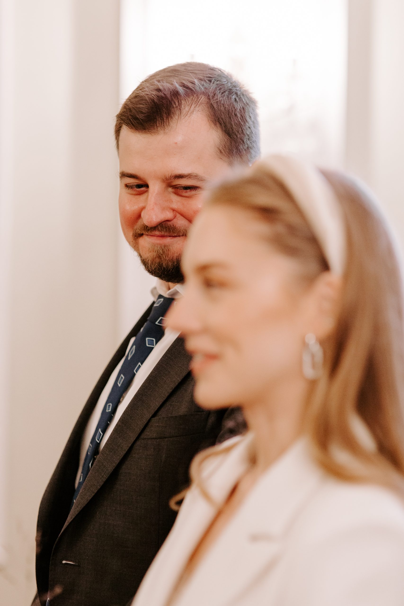 Groom smiling at bride as she says her vows in London