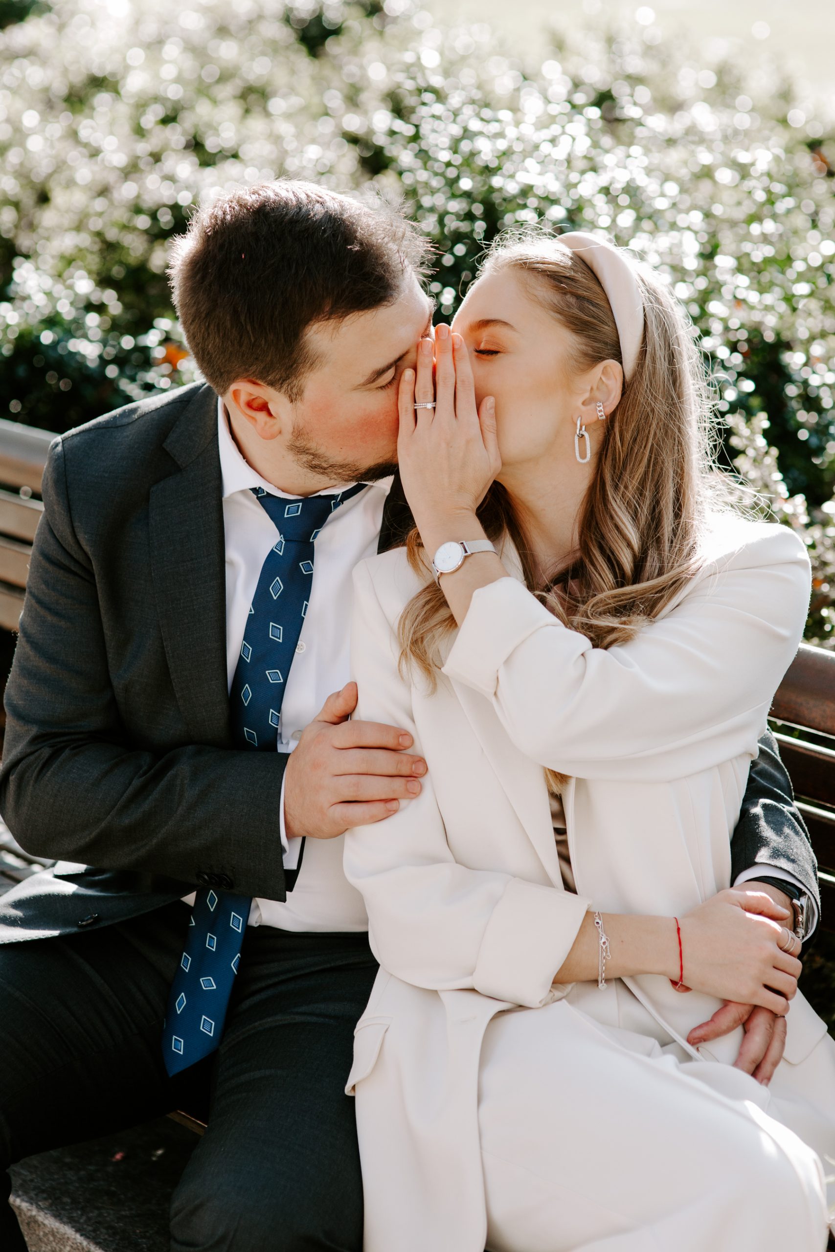 Bride and Groom kissing and hiding their face with hand to show wedding ring