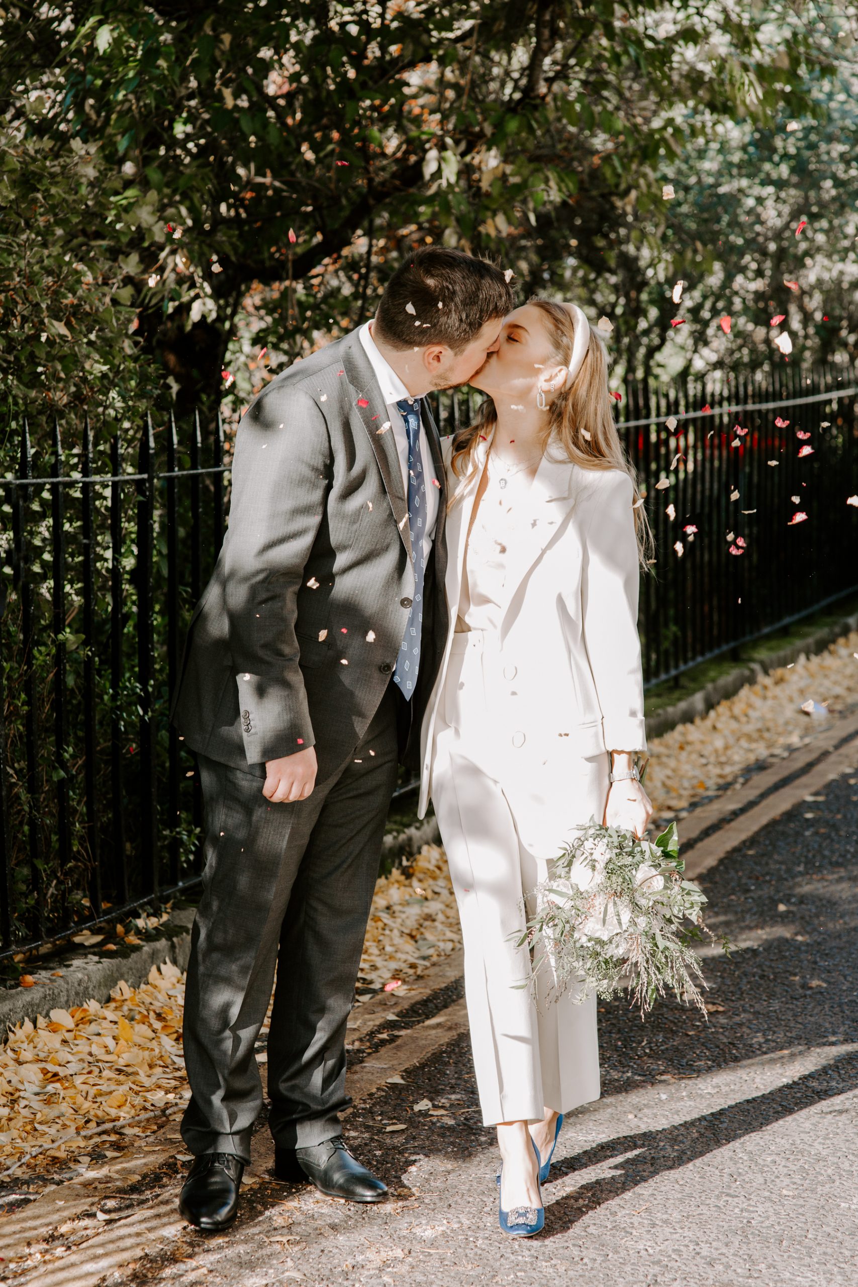 Bride and groom kissing under confetti throw in London