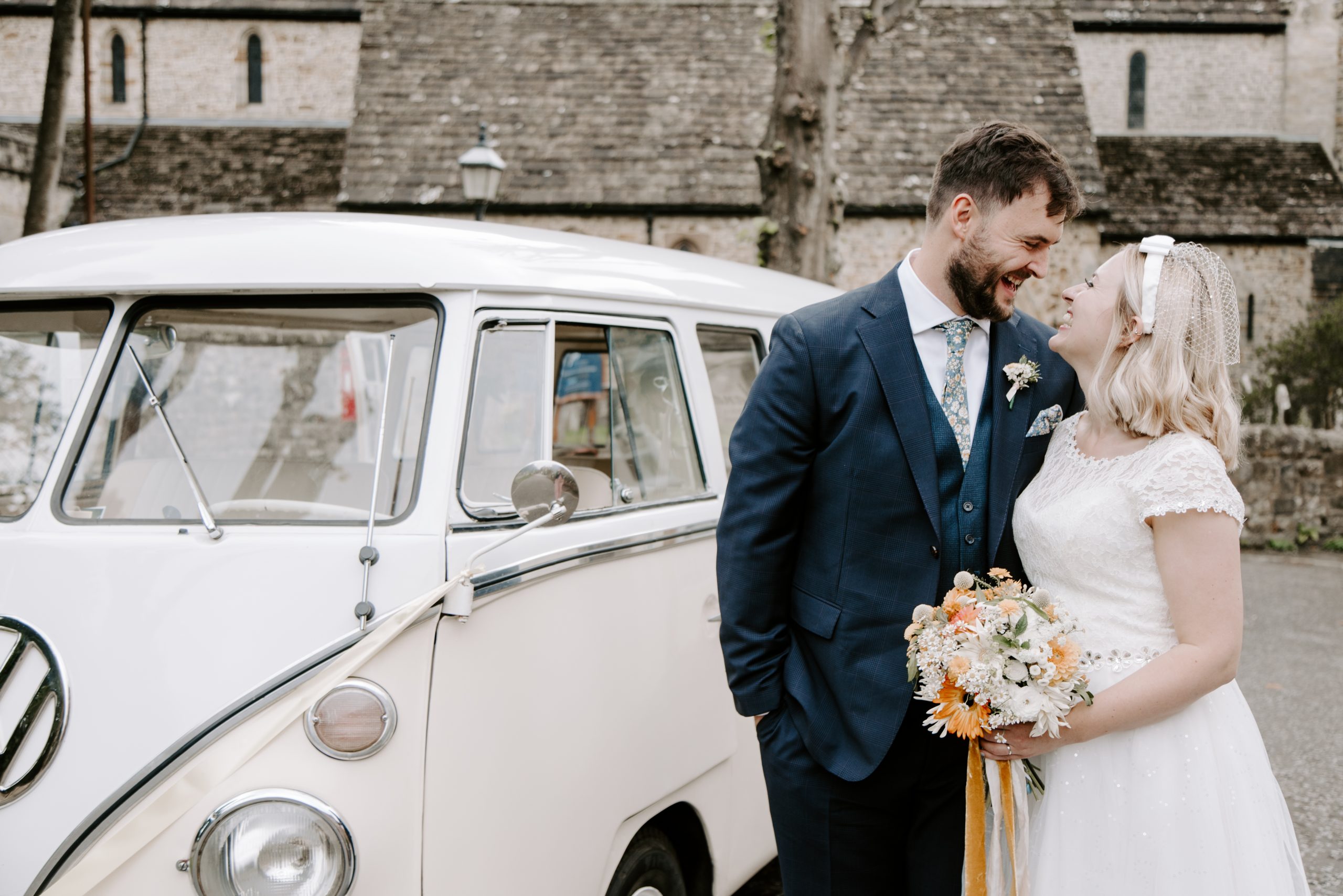 Bride and groom laughing in front of VW Campervan